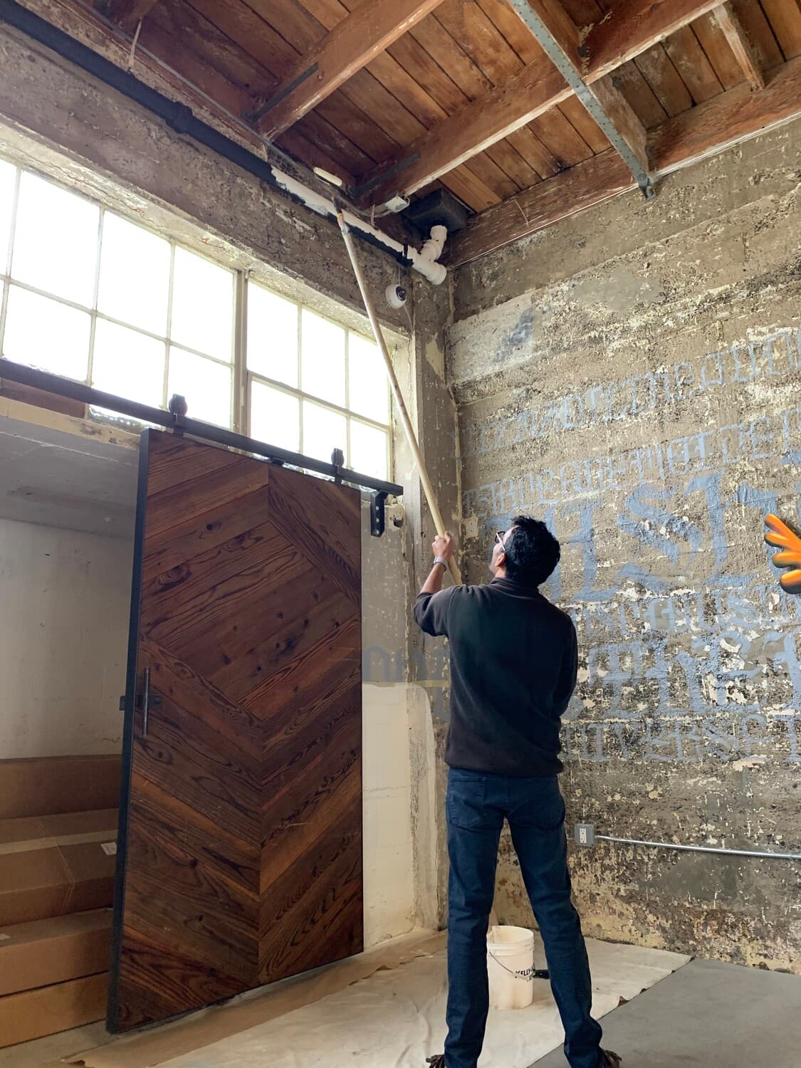 Picture of someone painting a high rafter of our former office